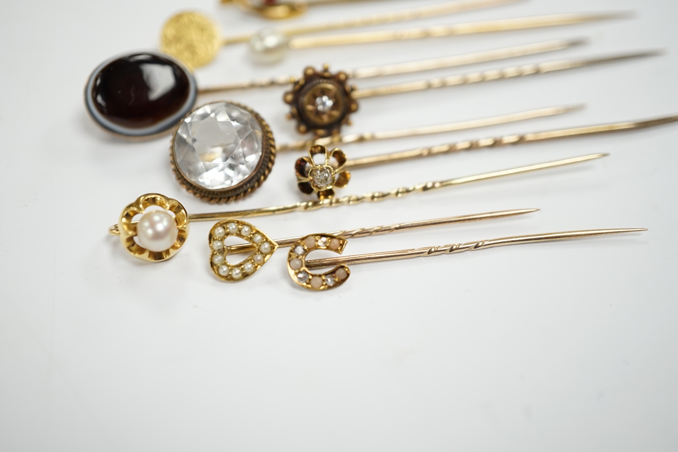 Fifteen assorted mainly early 20th century yellow metal and gem set stick pins, including diamond, seed pearl and banded agate, gross weight 23.1 grams.